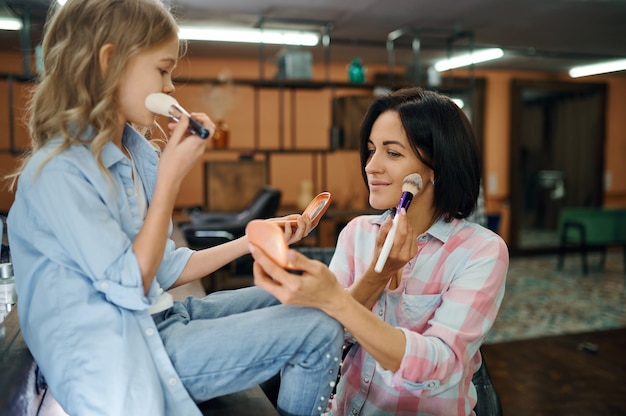 Moeder en dochter die poeder gebruiken in de make-up salon