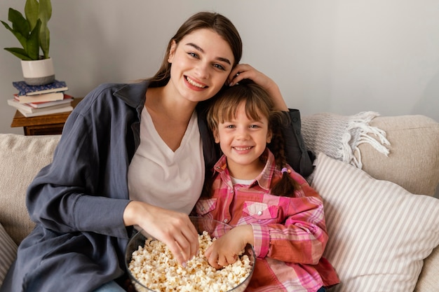 Moeder en dochter die thuis popcorn eten