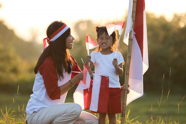 Moeder en dochter die vlag van Indonesië opheffen