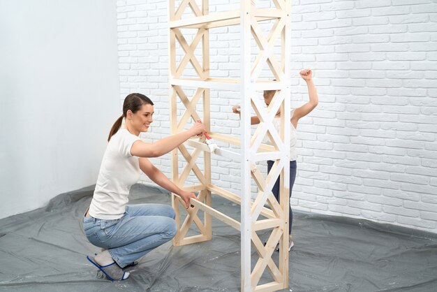 Moeder en dochter die witte verf op houten planken aanbrengen