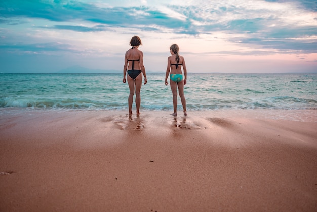 Moeder en dochter die zonsondergang strand bekijken