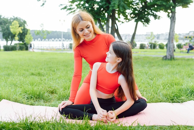 Moeder en dochter doen overdag yoga-oefeningen op gras in het park