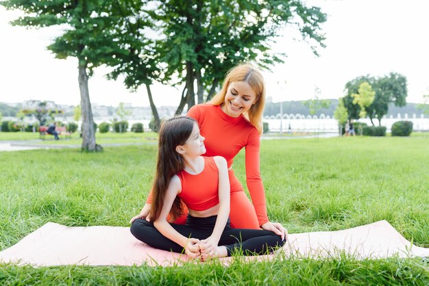 Moeder en dochter doen overdag yoga-oefeningen op gras in het park