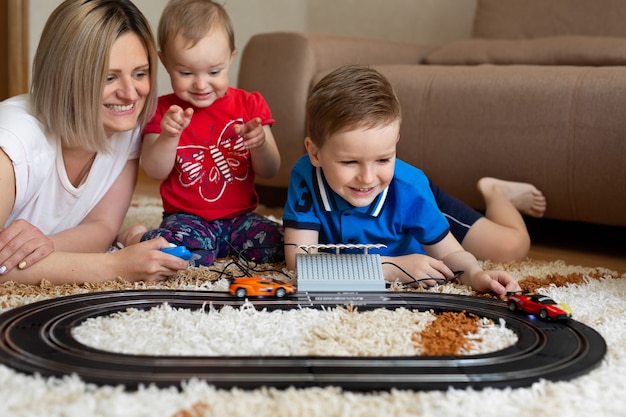 Moeder en dochter en zoon spelen racen op het tapijt.