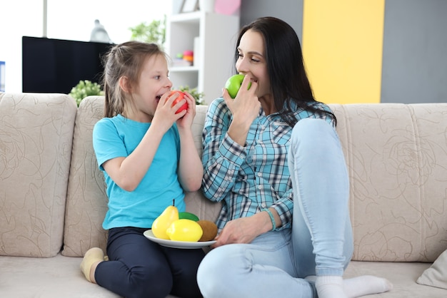 Moeder en dochter eten fruit terwijl ze op de bank zitten