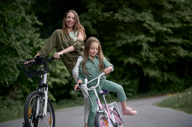 Moeder en dochter fietsen in het park Kinderen zomervakantie concept