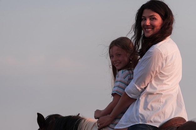 Moeder en dochter genieten van samen paardrijden aan zee selectieve focus