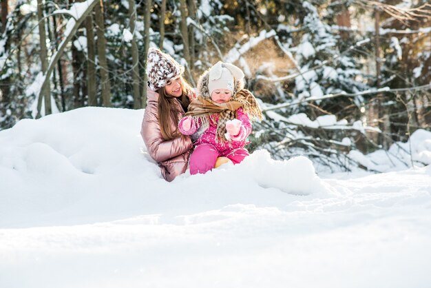 Moeder en dochter gewikkeld in een sjaal in een besneeuwd winterbos. reizen en recreatie