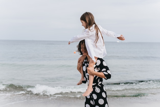 Moeder en dochter hand in hand en wandelen op het strand