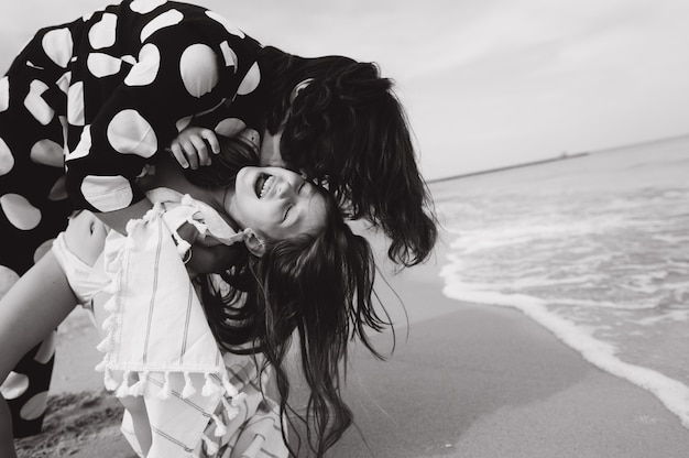 Moeder en dochter hand in hand en wandelen op het strand