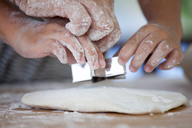 Moeder en dochter handen bereiden samen een deeg voor het bakken van koekjes