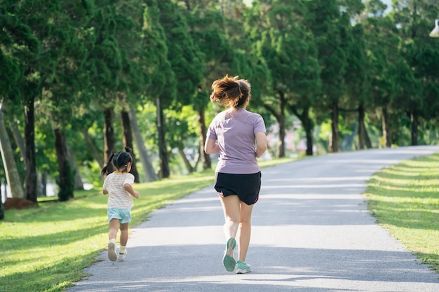 Moeder en dochter hardlopers joggen in het park Avond Familieactiviteiten Moeder en zoon in sportkleding rennen en hebben plezier