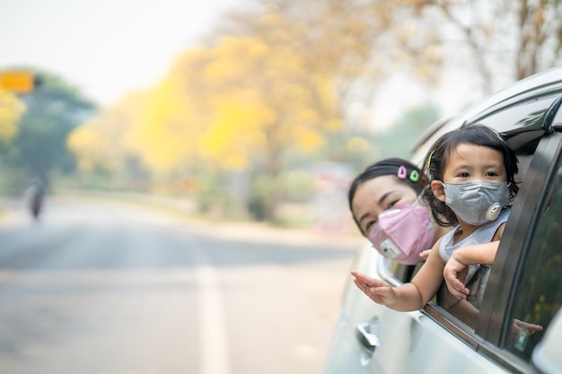 Moeder en dochter hebben plezier achterin een auto terwijl ze een beschermend masker dragen