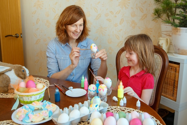 Moeder en dochter hebben plezier met het schilderen van eieren voor Pasen.