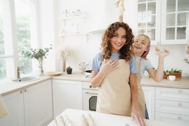 Moeder en dochter hebben plezier tijdens het koken van deeg in de keuken