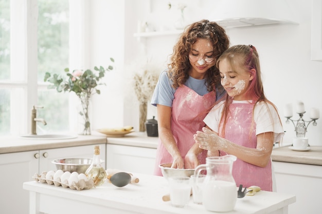 Moeder en dochter hebben plezier tijdens het koken van deeg in de keuken