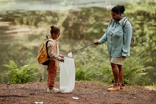 Moeder en dochter helpen de natuur schoon te maken en plastic flessen buitenshuis te plukken