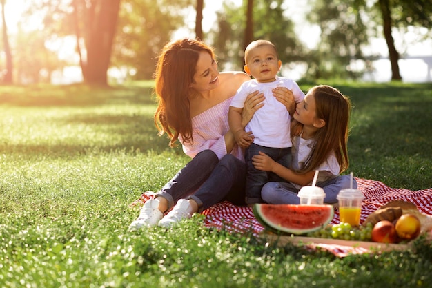 Moeder en dochter houden babyjongen op de handen in het park overdag