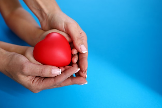 Moeder en dochter houden rood hart tegen blauw