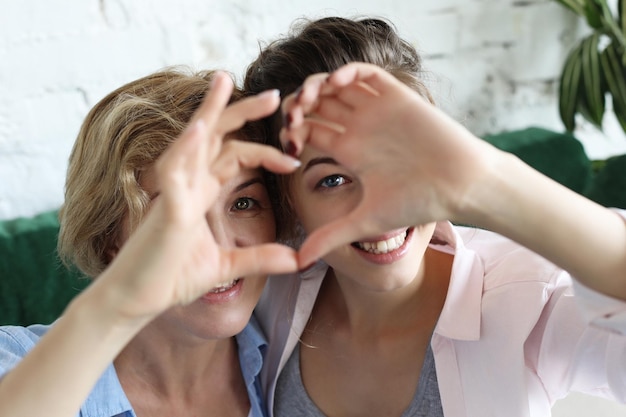 Moeder en dochter houden van volwassen vrouw en jonge vrouw stapelen handen in hartteken die camera bekijken