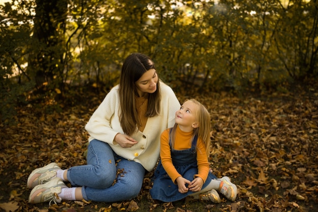 Moeder en dochter in de herfst loop ik tussen de gele bladeren en glimlach