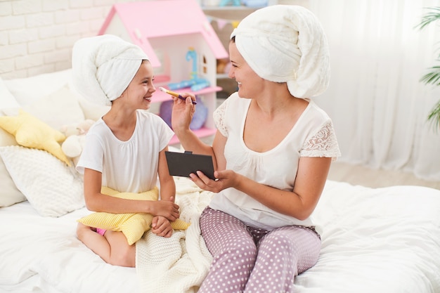 Moeder en dochter in handdoeken op hun hoofd, make-up en plezier hebben