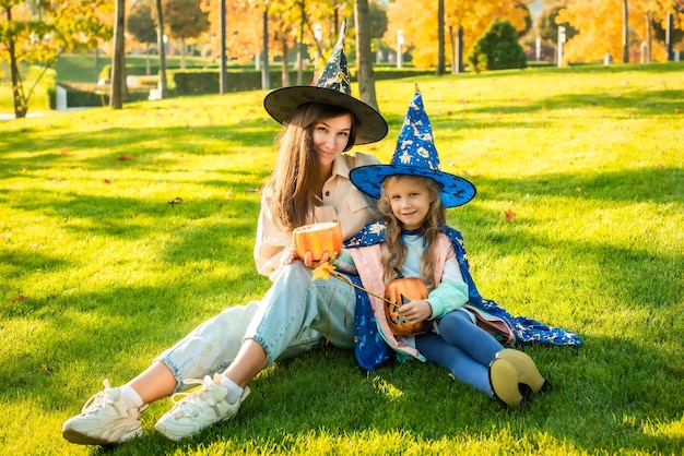 Moeder en dochter in kostuums en heksenhoeden in het park samen trick or treat Happy Halloween