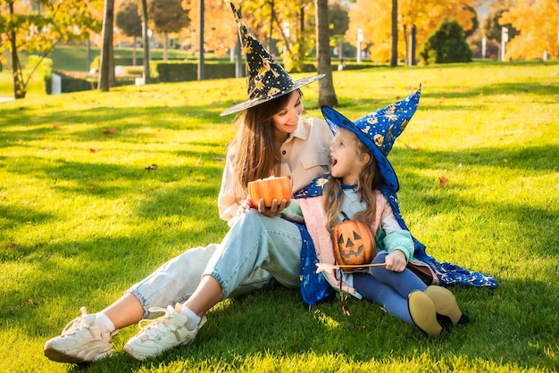 Moeder en dochter in kostuums en heksenhoeden in het park samen trick or treat Happy Halloween