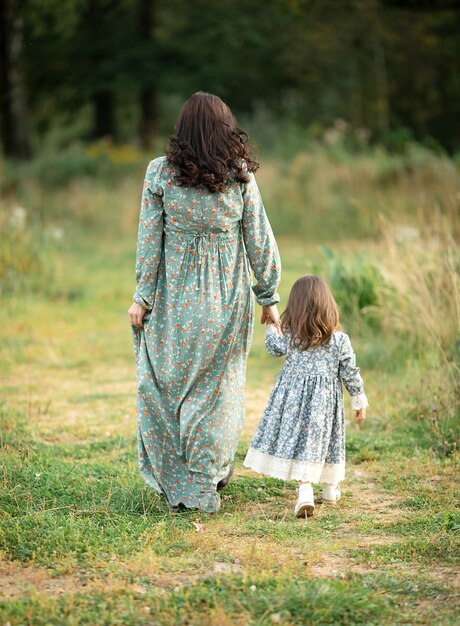 Moeder en dochter in prachtige vintage jurken wandelen in de natuur