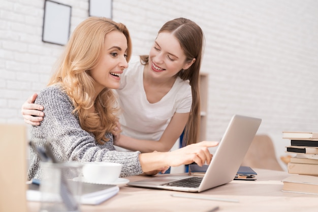 Moeder en dochter kijken naar laptop thuis.