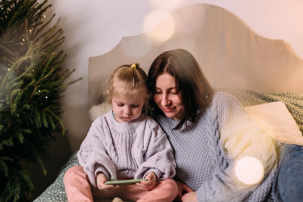 Moeder en dochter kijken samen met Kerstmis naar de smartphone