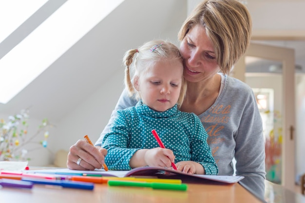 Moeder en dochter kleuren op een boek