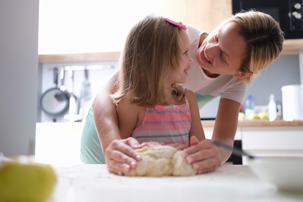 Moeder en dochter kneden samen deeg in de keuken