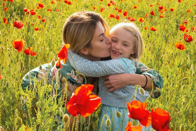 Moeder en dochter knuffelen op bloeiende papaver veld zomervakantie met het gezin op natuur zomer op popp