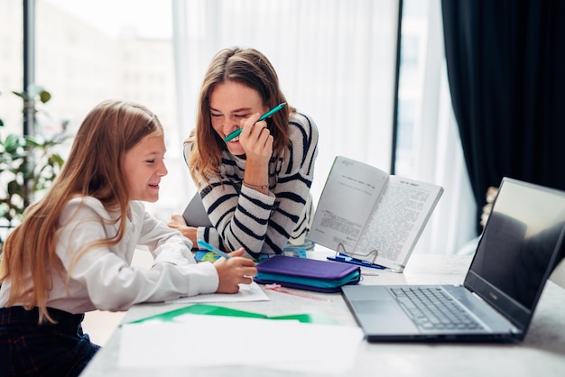 Moeder en dochter lachen terwijl ze huiswerk maken