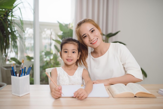 Moeder en dochter leren schrijven, moeder leert klein meisje huiswerk