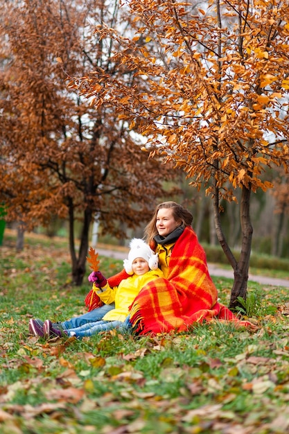 Moeder en dochter lezen een boek in het park Herfstplek voor tekst