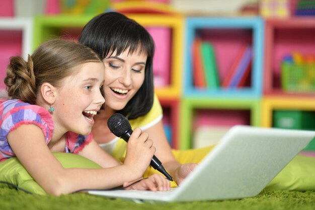 Moeder en dochter liggen op de vloer en zingen samen karaoke