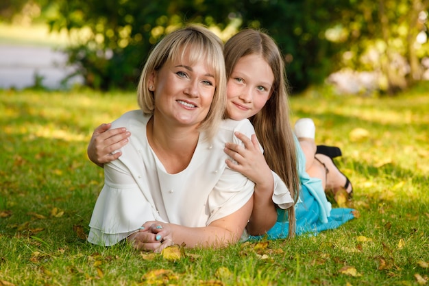 Moeder en dochter liggen op het gras in het zomerpark