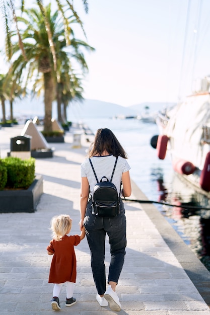 Moeder en dochter lopen hand in hand op een bootpier in Porto Montenegro.