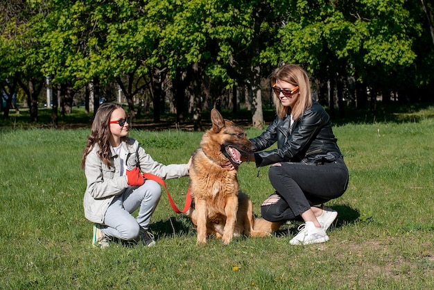 Moeder en dochter lopen in het park met een Duitse herdershond, emoties lachen en geluk