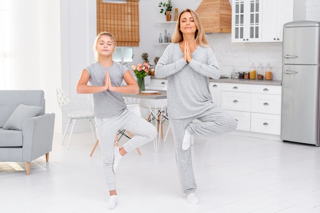 Foto moeder en dochter maken van yoga-oefeningen