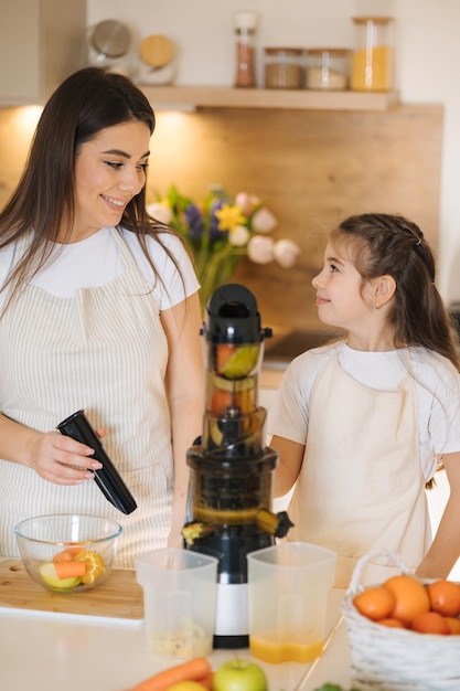Foto moeder en dochter maken zelfgemaakt gezond sap biologisch fruit en groenten veganistische drank