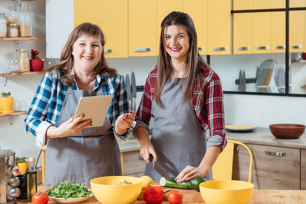 Moeder en dochter met behulp van tablet tijdens het koken in de keuken