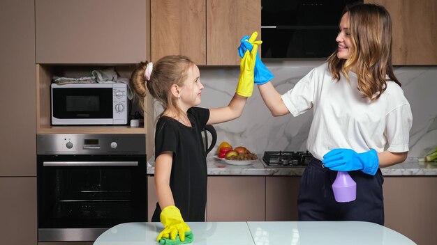 Moeder en dochter met handschoenen schone witte tafel in de keuken
