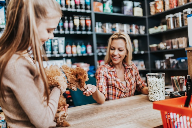 Moeder en dochter met hun poedelpuppy in dierenwinkel.