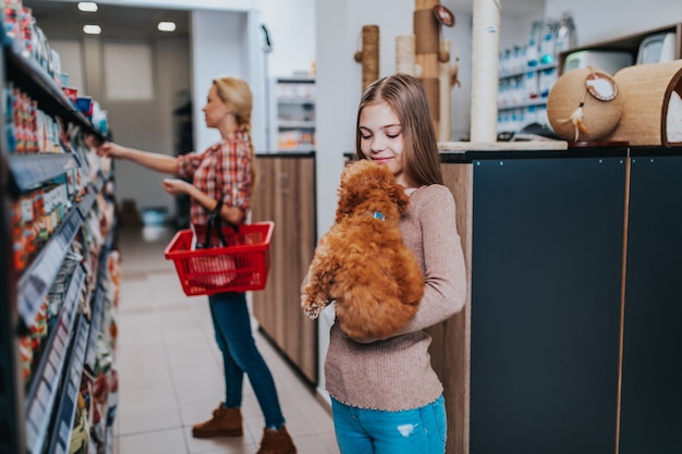 Moeder en dochter met hun poedelpuppy in dierenwinkel.