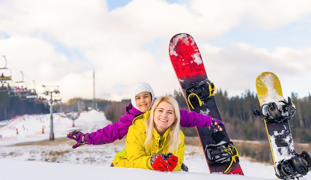 moeder en dochter met snowboards in een bergresort