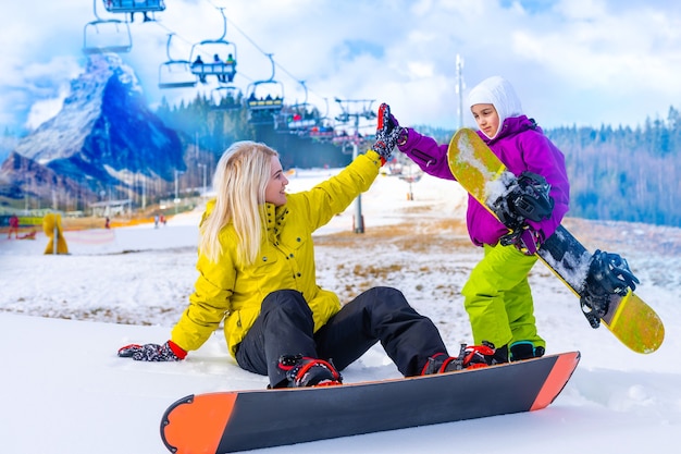 moeder en dochter met snowboards in een bergresort