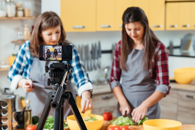 Moeder en dochter nemen een video op in de keuken voor hun kookblog